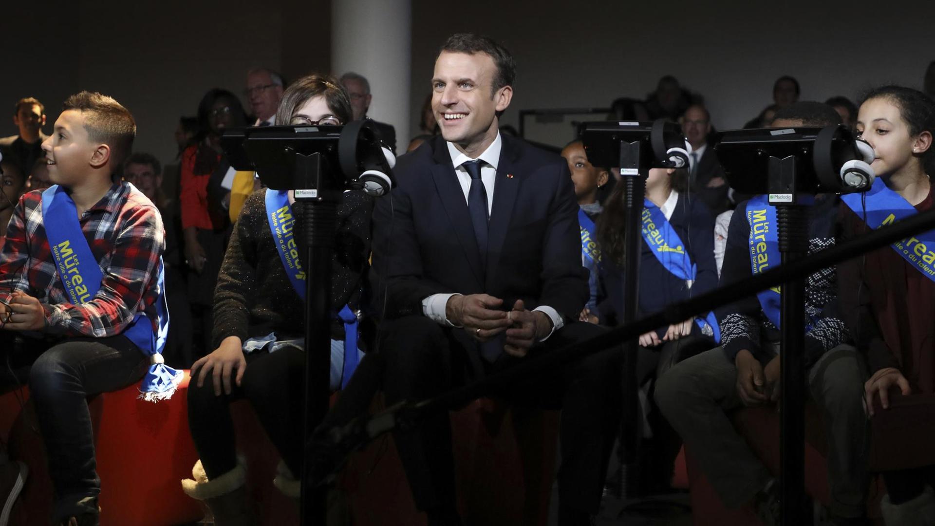 Emmanuel Macron sitzt am 20.2.2018 in der Micro-Folie von Les Mureaux zwischen mehreren Kindern.