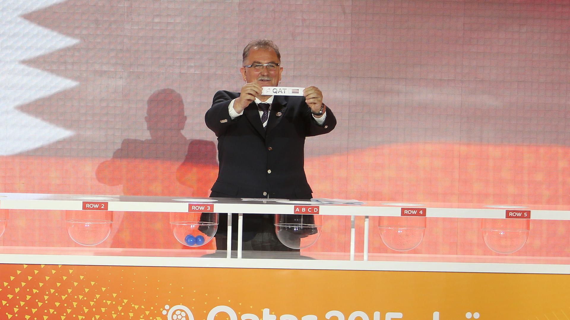 Leon Kalin, Mitorganisator der Handball-Weltmeisterschaft in Katar 2015 von der Internationalen Handball-Föderation (IHF), hält ein Los mit dem Namen von Katar bei der Ziehung der Spielpaarungen hoch. Leon Kalin, Mitorganisator der Handball-Weltmeisterschaft in Katar 2015 von der Internationalen Handball-Föderation (IHF), hält ein Los mit dem Namen von Katar bei der Ziehung der Spielpaarungen hoch.