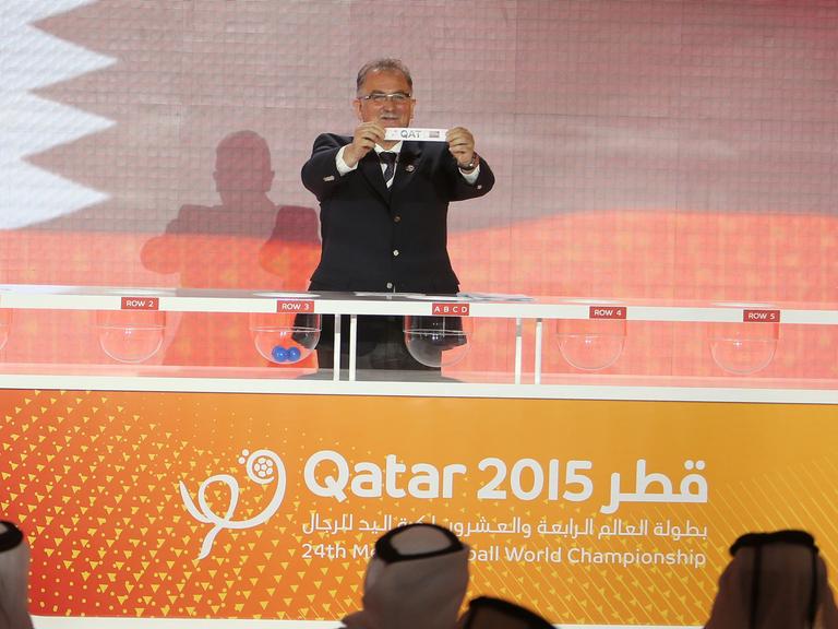 Leon Kalin, Mitorganisator der Handball-Weltmeisterschaft in Katar 2015 von der Internationalen Handball-Föderation (IHF), hält ein Los mit dem Namen von Katar bei der Ziehung der Spielpaarungen hoch.