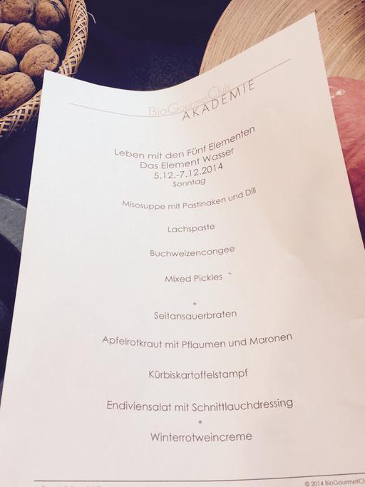 Ein Rezept liegt auf einem Tisch mit Kürbissen und Walnüssen.