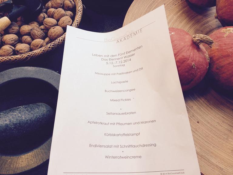Ein Rezept liegt auf einem Tisch mit Kürbissen und Walnüssen.