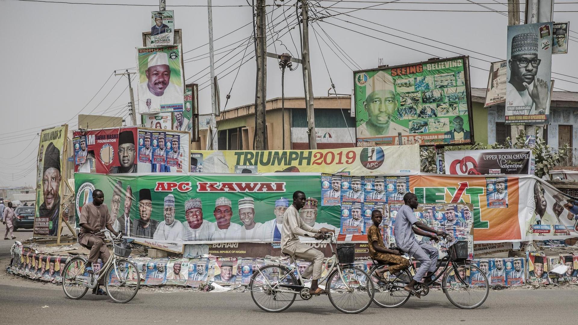 Menschen fahren auf Räder in der nigerianischen Stadt Mubi im Staat Adamawa an Wahlkampf-Plakaten vorbei. Die Wahl wird sich vor allem zwischen Präsident Muhammadu Buhari und seinem wichtigsten Herausforderer, Atiku Abubakar, entscheiden. Menschen fahren auf Räder in der nigerianischen Stadt Mubi im Staat Adamawa an Wahlkampf-Plakaten vorbei. Die Wahl wird sich vor allem zwischen Präsident Muhammadu Buhari und seinem wichtigsten Herausforderer, Atiku Abubakar, entscheiden.