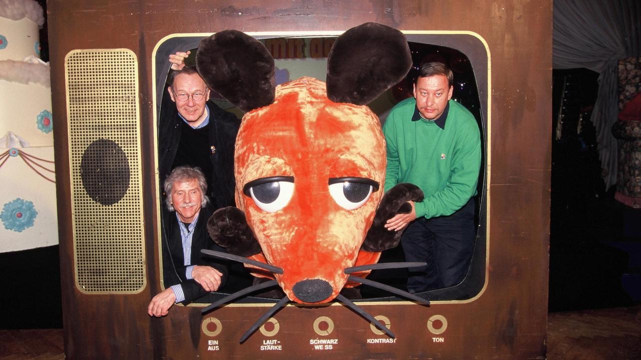 Der Zeichner der TV-Maus, Friedrich Streich (links unten), und die beiden Autoren der Sach- und Lachgeschichten Christoph Biemann (r) und Armin Maiwald (l) posieren mit der Maus.