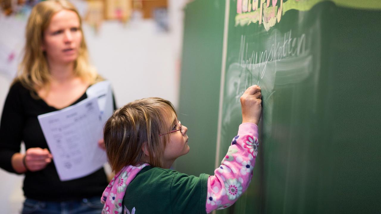 Die neunjährige Cora schreibt, beobachtet von Klassenlehrerin Anne John, in der Freien Schule in Bröbberow an die Schultafel. Die neunjährige Cora schreibt, beobachtet von Klassenlehrerin Anne John, in der Freien Schule in Bröbberow an die Schultafel.