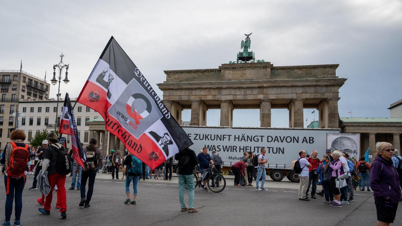 Ein Demonstrant hält vor einer Demonstration gegen die Corona-Maßnahmen eine große Reichsflagge vor dem Brandenburger Tor.