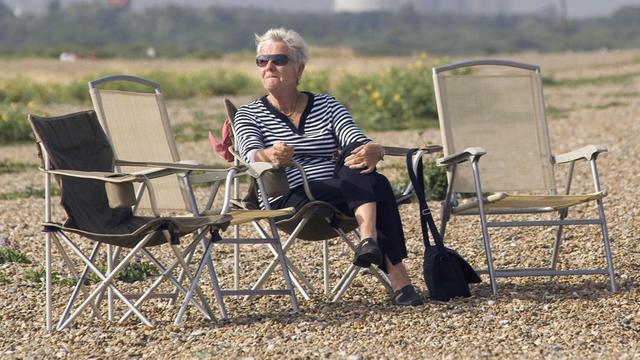 Eine Frau sitzt am Strand von Aldeburgh in Großbritannien auf einem Klappstuhl und genießt die Sonne, aufgenommen im Juli 2005.