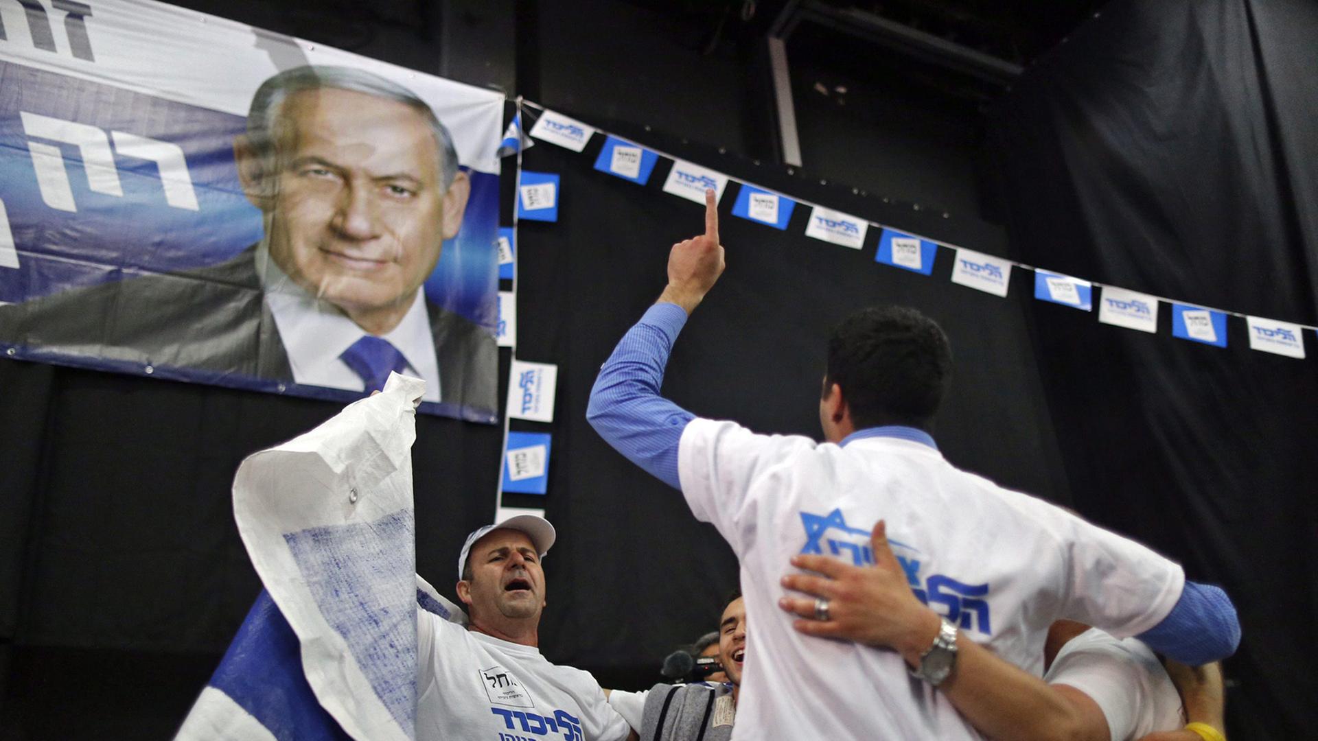 Männer mit Partei-T-Shirts bekleidet tanzen im Kreis unter einer Flagge mit dem Bild von Benjamin Netanjahu Männer mit Partei-T-Shirts bekleidet tanzen im Kreis unter einer Flagge mit dem Bild von Benjamin Netanjahu