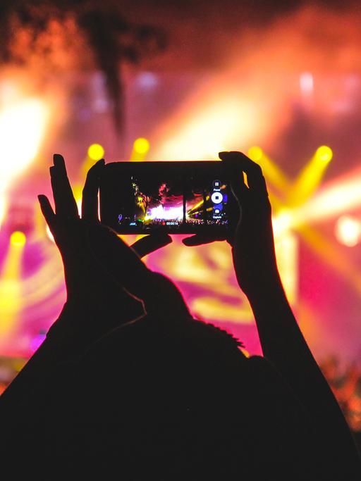 Konzertbesucher filmen die Band mit dem Handy.