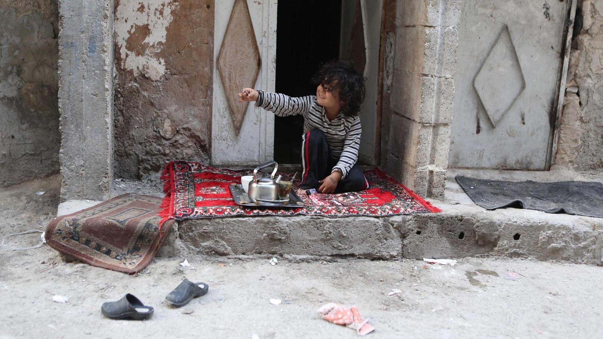 Ein syrischer Junge sitzt vor seinem Haus in Tishreen am ersten Tag des Waffenstillstands in Syrien. Ein syrischer Junge sitzt vor seinem Haus in Tishreen am ersten Tag des Waffenstillstands in Syrien.