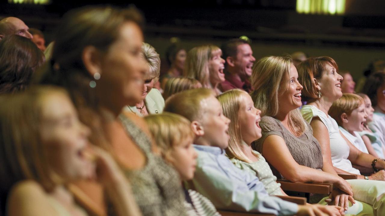 Kinder, Frauen und Männer sitzen vergnügt und lachend in einer Theatervorstellung. Kinder, Frauen und Männer sitzen vergnügt und lachend in einer Theatervorstellung.