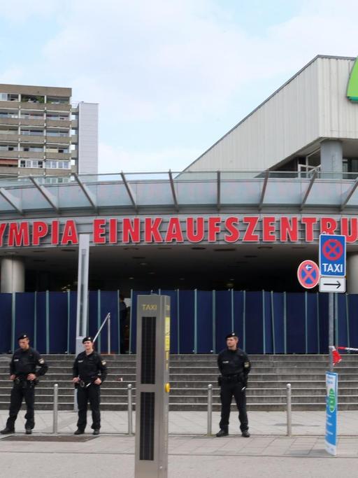 Polizeibeamte stehen am 23.07.2016 vor dem Olympia-Einkaufszentrum OEZ in München (Bayern), einen Tag nach einer Schießerei mit Toten und Verletzten.