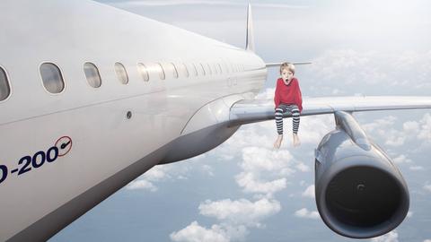 Fotomontage: Sechsjähriger Junge sitzt mit weit aufgerissenem Mund während des Fluges auf der Tragfläche eines Airbus A320