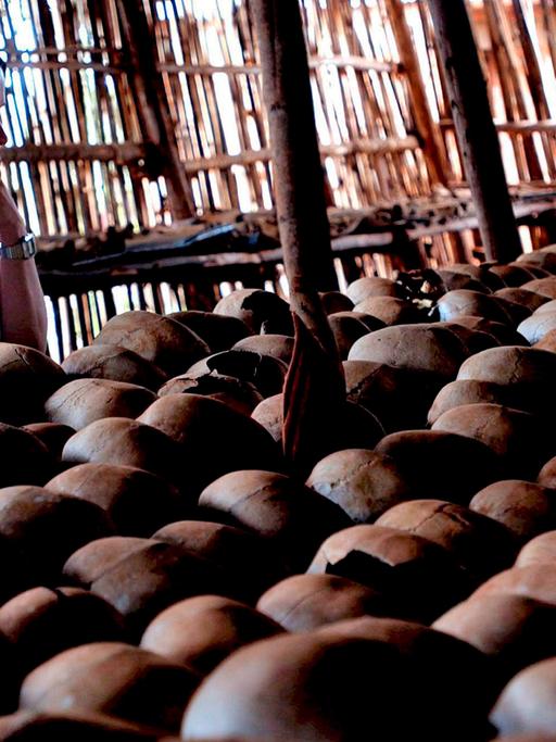Eine Frau steht vor einer Schädelreihe: Gedenkstätte für den Völkermord in Ruanda