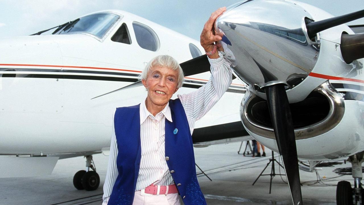 Beate Uhse steht vor ihrem Privatjet, sie hält ihre Hand auf die silberne Spitze ihres Flugzeugs.