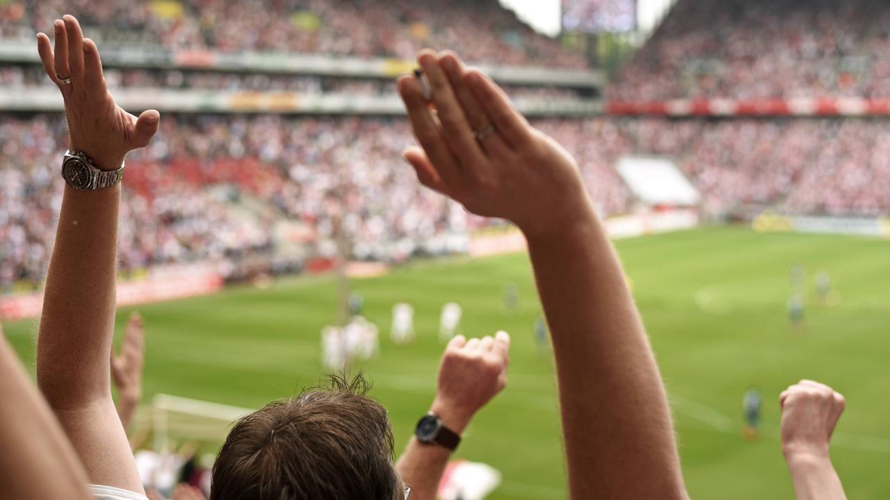 Fußballfans in der Fankurve werfen die Hände in die Luft. Fußballfans in der Fankurve werfen die Hände in die Luft.
