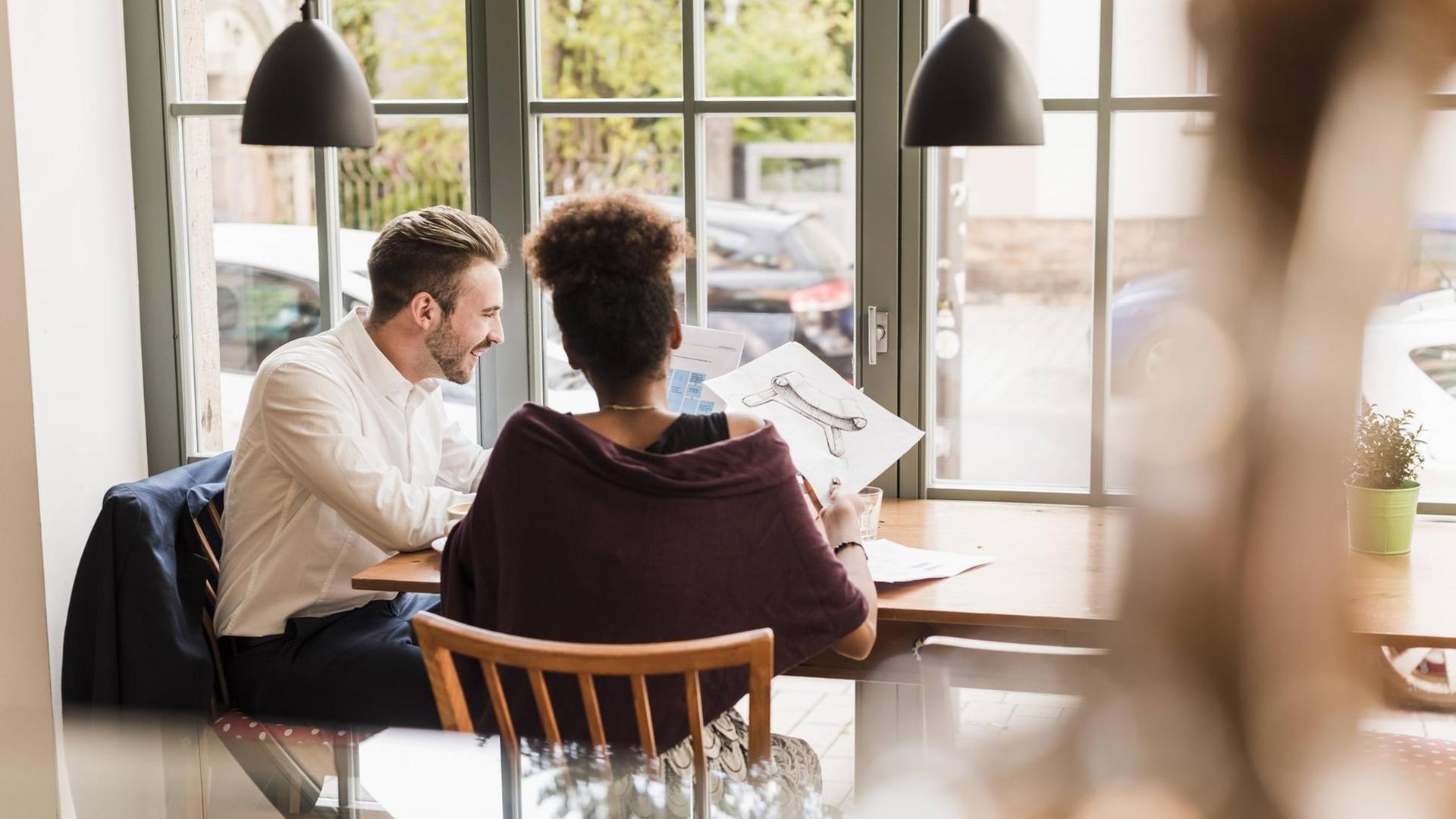 Ein junger Mann und eine Frau sitzen in einem Café. Ein junger Mann und eine Frau sitzen in einem Café.