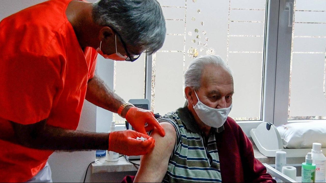 Impfung gegen das Coronavirus - ein älterer Mann bekommt eine Spritze verabreicht