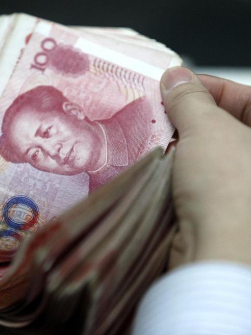 Ein Mensch in China zählt Yuan-Scheine