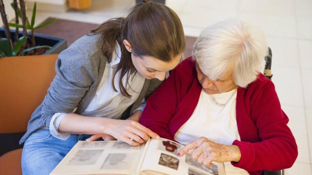 Großmutter betrachtet mit Enkeltochter ein altes Fotoalbum