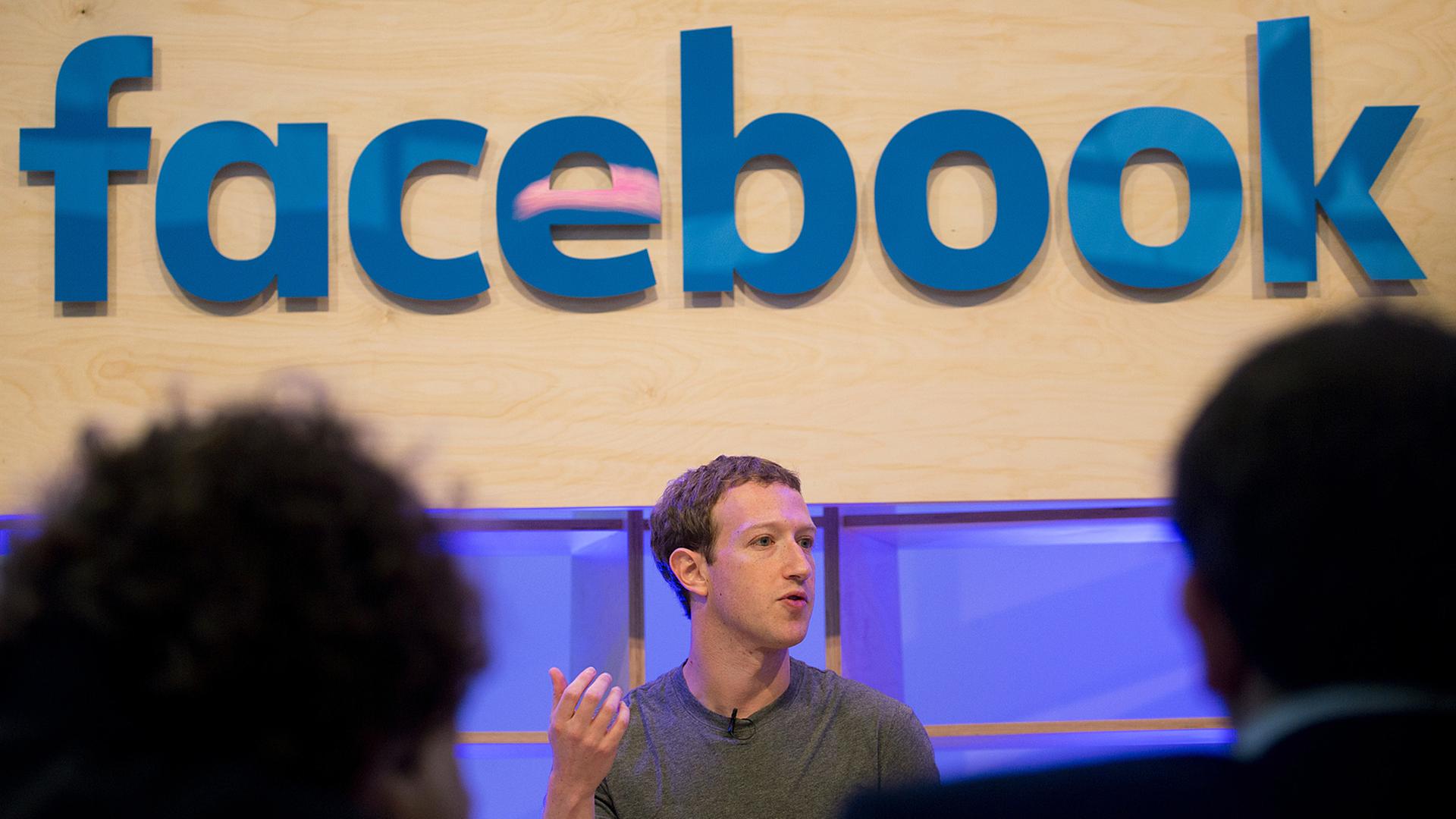 Facebook-Chef Mark Zuckerberg bei einer Veranstaltung, über ihm das Facebook-Logo