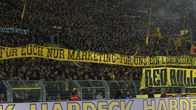 Dortmunder Fans zeigen während des Spieles Borussia Dortmund gegen RB Leipzig im Signal-Iduna-Park Transparente mit der Aufschrift "Für Euch nur Marketing - Für uns ein Lebenssinn" und "Red Bull - Feind des Fußballs".
