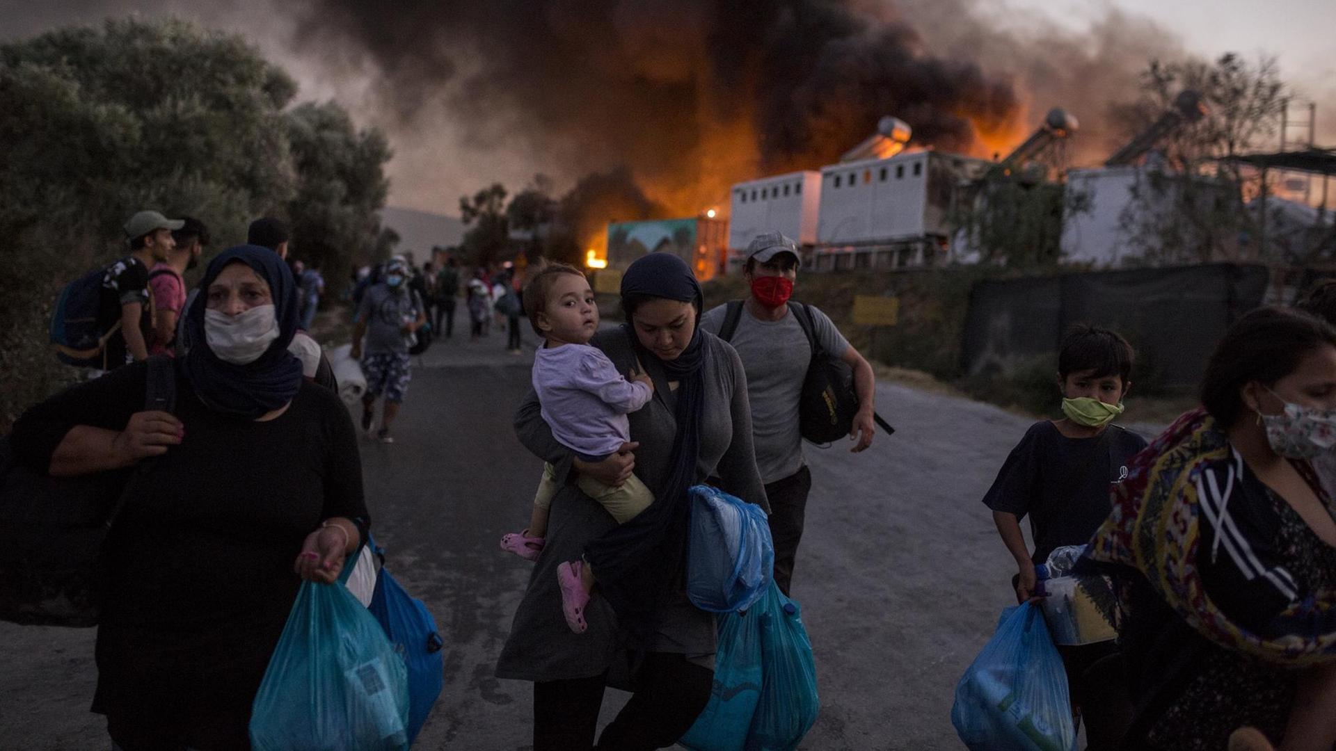 Griechenland, Moria: Migranten fliehen vor neu ausgebrochenen Feuern mit ihren Habseligkeiten aus dem Flüchtlingslager Moria, nachdem zuvor bereits mehrere Brände das Lager nahezu vollständig zerstört hatten. Vorangegangen waren Unruhen unter den Migranten, weil das Lager nach einem ersten Corona-Fall unter Quarantäne gestellt worden war. Griechenland, Moria: Migranten fliehen vor neu ausgebrochenen Feuern mit ihren Habseligkeiten aus dem Flüchtlingslager Moria, nachdem zuvor bereits mehrere Brände das Lager nahezu vollständig zerstört hatten. Vorangegangen waren Unruhen unter den Migranten, weil das Lager nach einem ersten Corona-Fall unter Quarantäne gestellt worden war.
