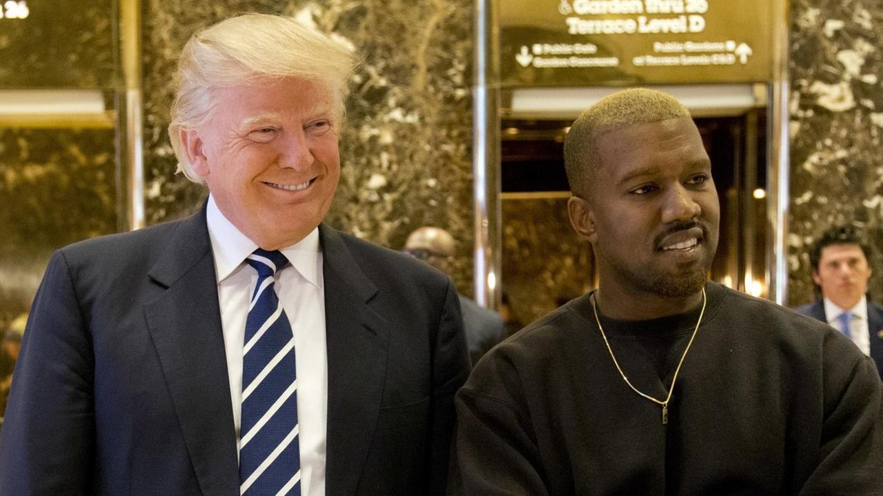 US-Präsident Donald Trump und Rapper Kanye West nebeneinander vor den Aufzügen im New Yorker Trump Tower