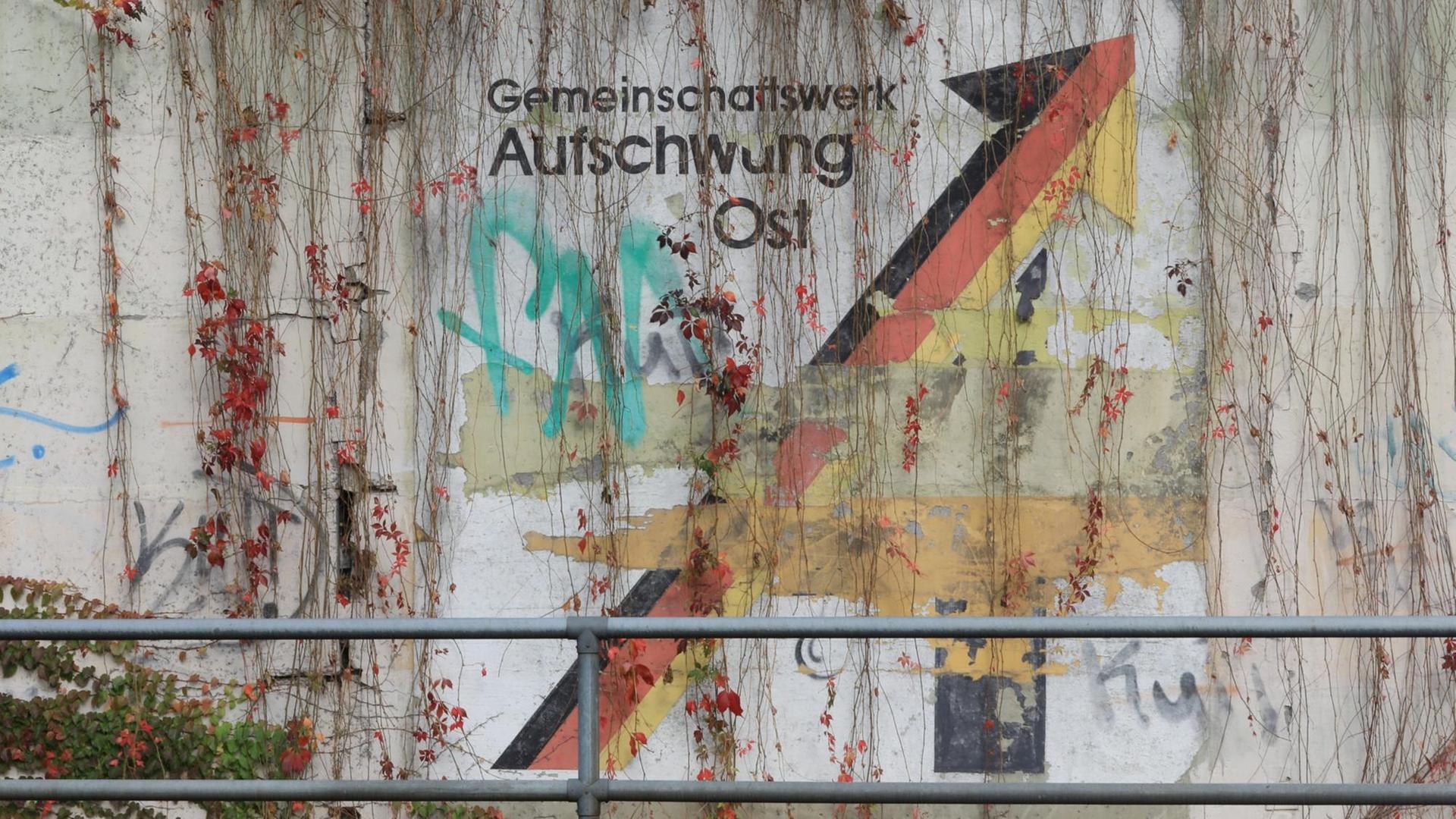 An einer Schallschutzwand in Magdeburg prangt der verwitterte Schriftzug "Gemeinschaftswerk Aufschwung Ost". An einer Schallschutzwand in Magdeburg prangt der verwitterte Schriftzug "Gemeinschaftswerk Aufschwung Ost".