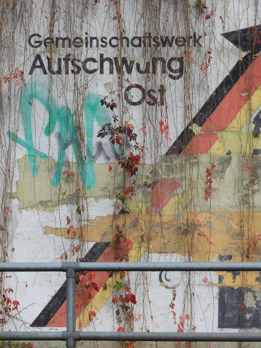 An einer Schallschutzwand in Magdeburg prangt der verwitterte Schriftzug "Gemeinschaftswerk Aufschwung Ost".