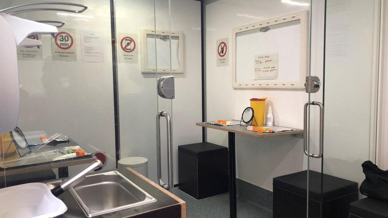 Im Innenraum des Drogenkonsum-Mobils befinden sich mehrere, durch Glaswände abgetrennte Kabinen. Auf schwarzen, würfelförmigen Hockern sitzend, können Suchtkranke unter hygienischen Bedingungen ihre Drogen konsumieren. Im Innenraum des Drogenkonsum-Mobils befinden sich mehrere, durch Glaswände abgetrennte Kabinen. Auf schwarzen, würfelförmigen Hockern sitzend, können Suchtkranke unter hygienischen Bedingungen ihre Drogen konsumieren.