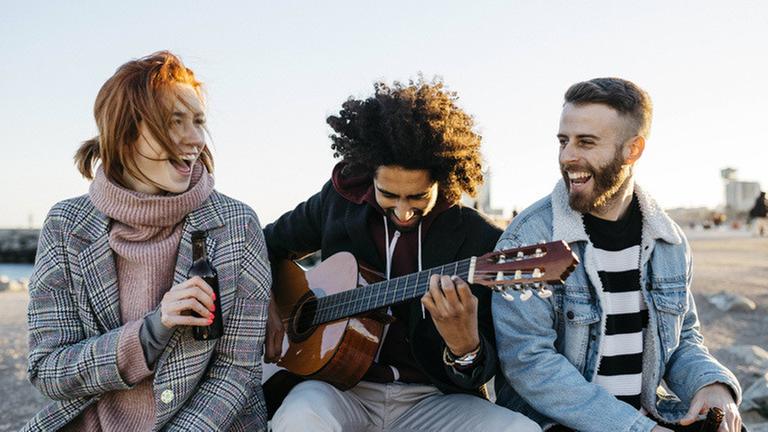 Three happy friends with guitar sitting outdoors at sunset model released Symbolfoto PUBLICATIONxINxGERxSUIxAUTxHUNxONLY JRFF02654 Three happy friends with guitar sitting outdoors at sunset model released Symbolfoto PUBLICATIONxINxGERxSUIxAUTxHUNxONLY JRFF02654