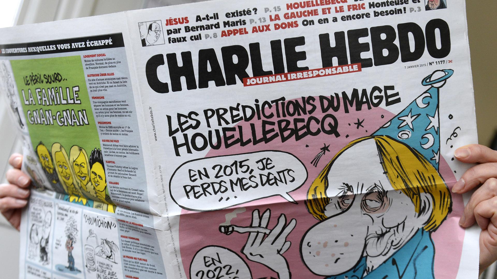 Eine Person hält die Ausgabe der Zeitschrift "Charlie Hebdo" vom 7. Januar 2015 in Händen. Eine Person hält die Ausgabe der Zeitschrift "Charlie Hebdo" vom 7. Januar 2015 in Händen.