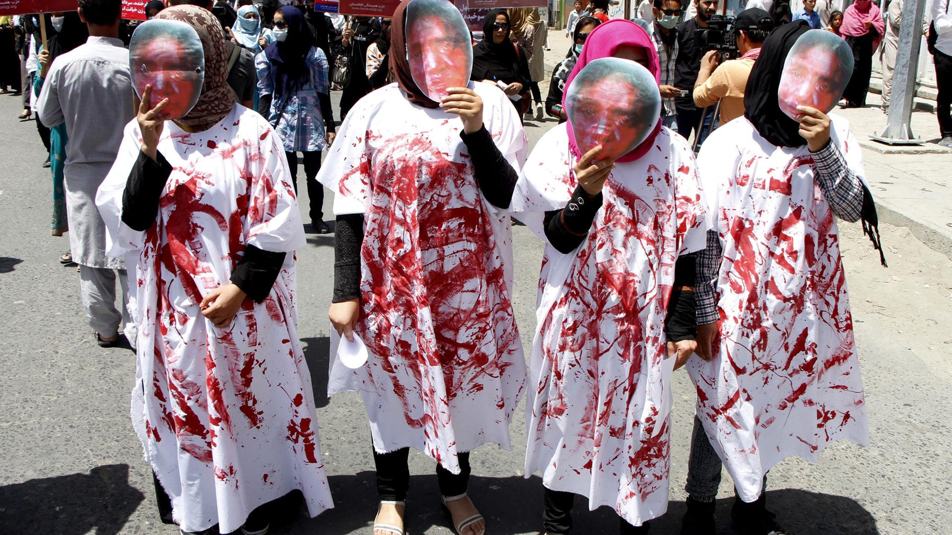Vier Frauen tragen bei einer Demonstration in Kabul Masken, die das blutverschmierte Gesicht von Farkhunda Malikzada zeigen Vier Frauen tragen bei einer Demonstration in Kabul Masken, die das blutverschmierte Gesicht von Farkhunda Malikzada zeigen