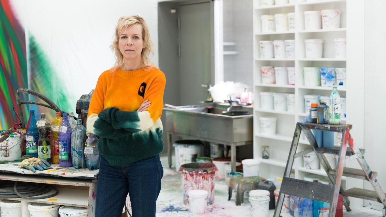 Katharina Grosse steht in ihrem Atelier und blickt in Richtung des Betrachters. Katharina Grosse steht in ihrem Atelier und blickt in Richtung des Betrachters.