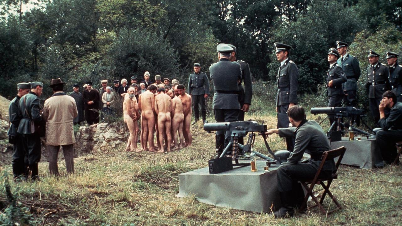 Filmszene: Nackte Männer, davor Wehrmachtssoldaten an Maschinengewehren Filmszene: Nackte Männer, davor Wehrmachtssoldaten an Maschinengewehren
