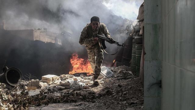 Ein Jaish-al-Islam-Kämpfer flieht in dem syrischen Dorf Tal al-Siwan vor Schüssen, hinter ihm brennt es.