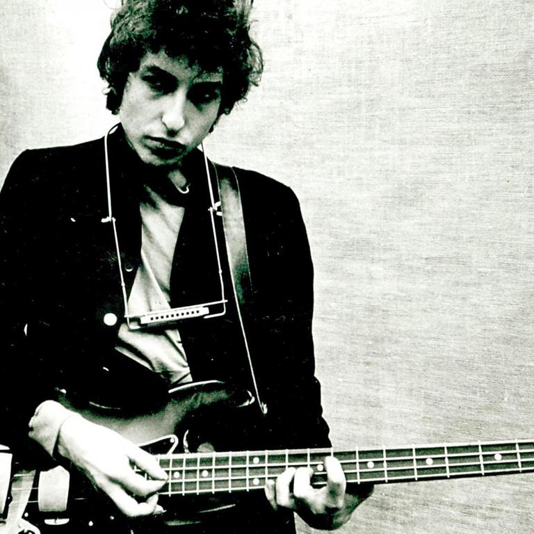 Bob Dylan spielt sein Fender Jazz Bass mit der Mundharmonika um seinen Hals, während er sein Album 'Bringing It All Back Home' aufnimmt. 1965 in Columbia's Studio A in New York City, New York.