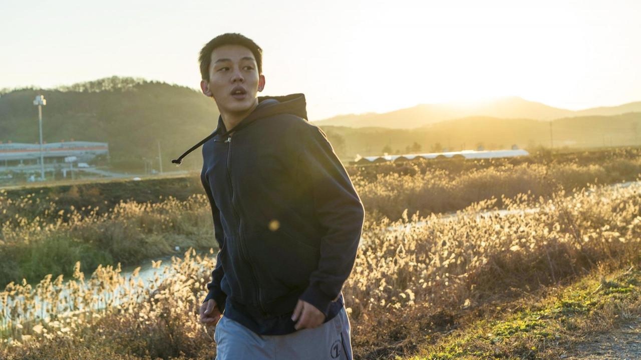 Ein junger Koreaner läuft über eine Wiese. Er schaut seitlich an der Kamera vorbei. Ein junger Koreaner läuft über eine Wiese. Er schaut seitlich an der Kamera vorbei.