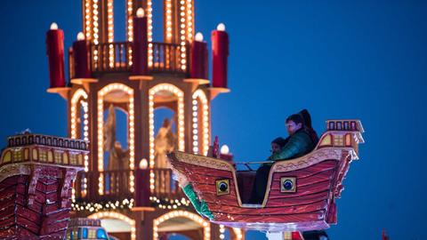 Besucher sitzen am 01.12.2017 auf dem eröffneten Weihnachtsmarkt an der Landsberger Allee in Berlin in einem Kinder-Karussell. Nach Veranstalterangaben steht auf dem Rummelplatz in Berlin-Lichtenberg neben zahlreichen Fahrgeschäften die mit 26,5 Meter Höhe größte Weihnachtspyramide der Welt.