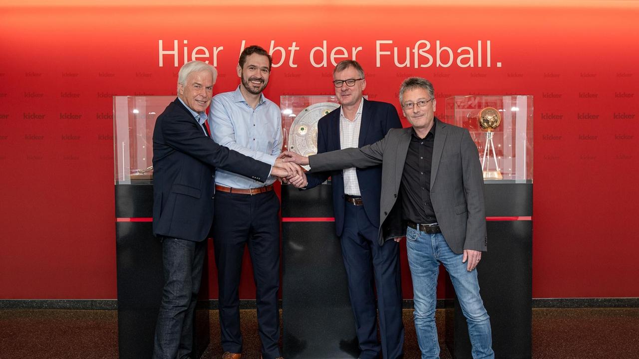 "Kicker"-Chefredakteur Jörg Jakob (3.v.l.), Herausgeber Rainer Holzschuh (l.), Sportfunktionär Friedrich Curtius (2.v.l.) und Redakteur Alexander Wagner stehen vorin Vitrinen ausgestellten Trophäen. Darüber der Schriftzug: "Hier lebt der Fußball". "Kicker"-Chefredakteur Jörg Jakob (3.v.l.), Herausgeber Rainer Holzschuh (l.), Sportfunktionär Friedrich Curtius (2.v.l.) und Redakteur Alexander Wagner stehen vorin Vitrinen ausgestellten Trophäen. Darüber der Schriftzug: "Hier lebt der Fußball".