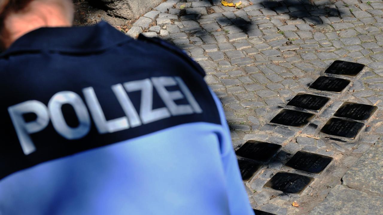 Eine Polizistin schaut sich am 06.06.2013 in Berlin in der Stierstraße im Stadtteil Friedenau beschmierte Stolpersteine an.
