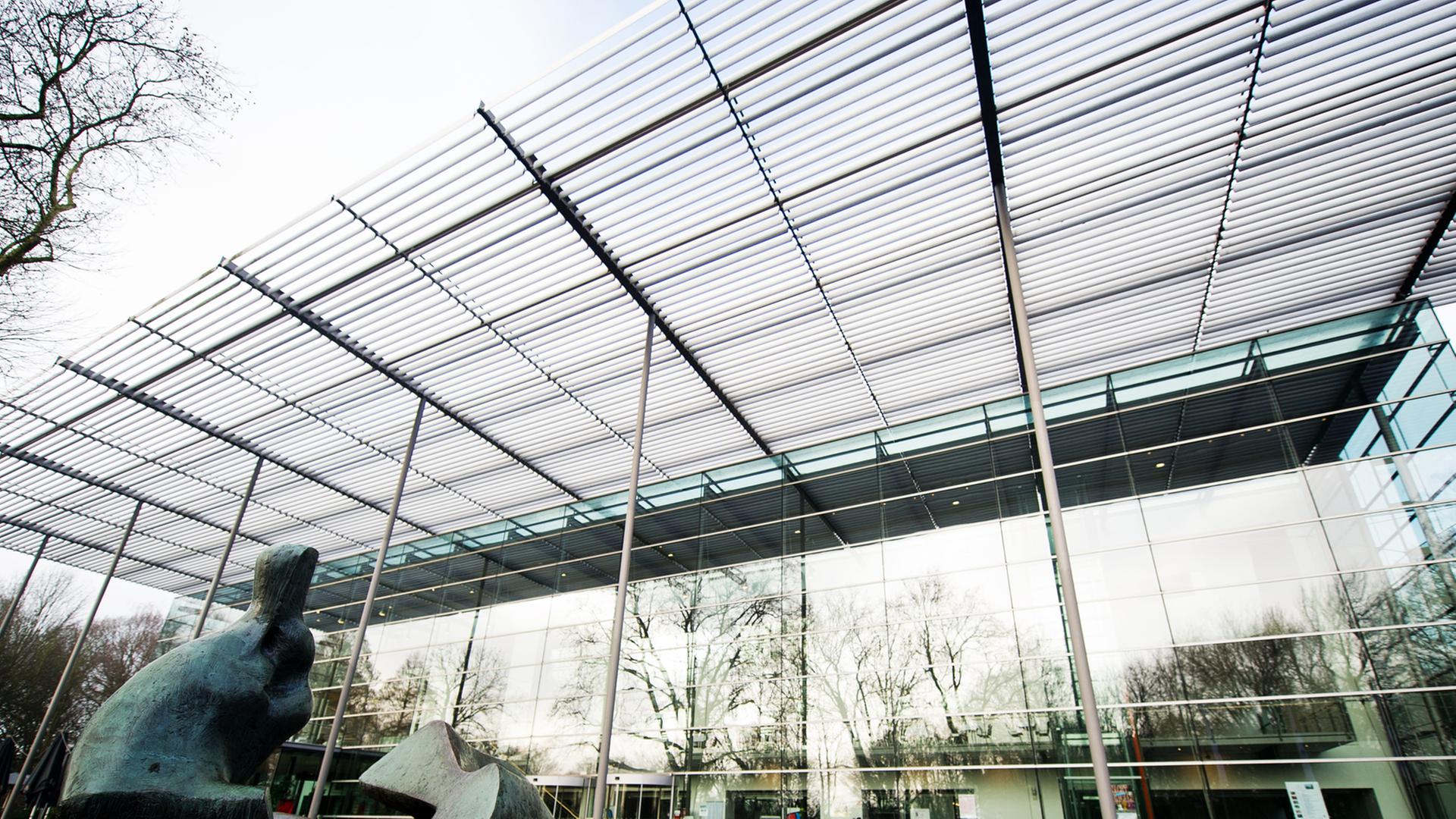 Halle der Ruhrfestspiele in Recklinghausen, Blick vom Boden auf ein Glasgebäude, im Vordergrund eine Skulptur Halle der Ruhrfestspiele in Recklinghausen, Blick vom Boden auf ein Glasgebäude, im Vordergrund eine Skulptur