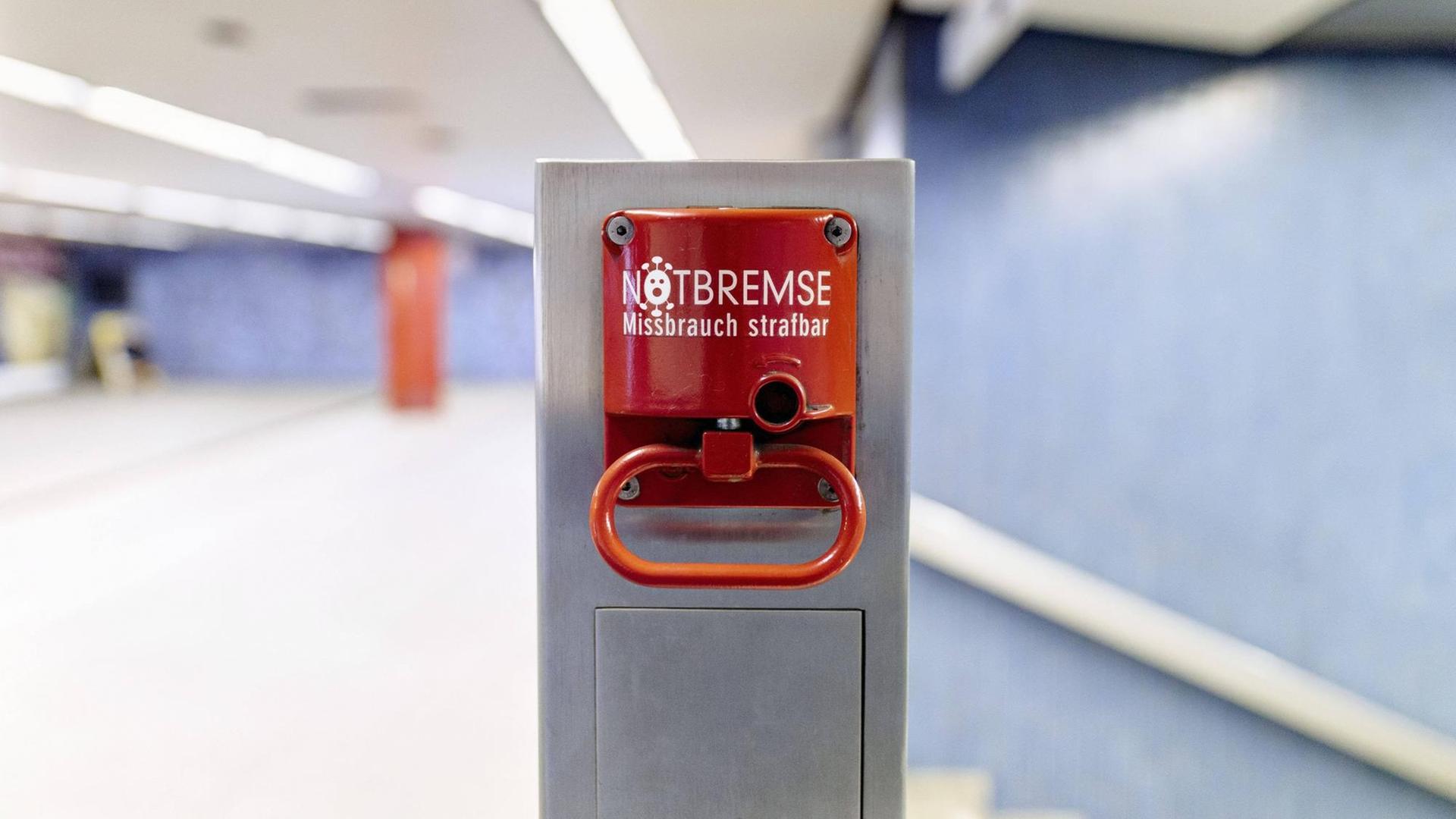 Eine Notbremse auf einem Bahnsteig mit einem Coronavirus an Stelle des "O". Eine Notbremse auf einem Bahnsteig mit einem Coronavirus an Stelle des "O".
