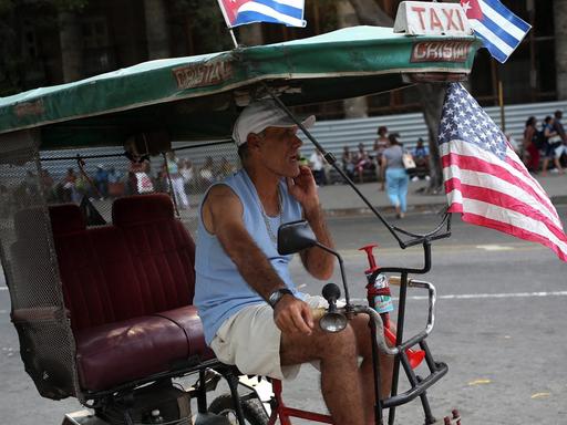 Auf dem Bild ist ein Radfahrer in Havanna zu sehen, der die kubanische und die US-Flagge an seinem Rad befestigt hat.