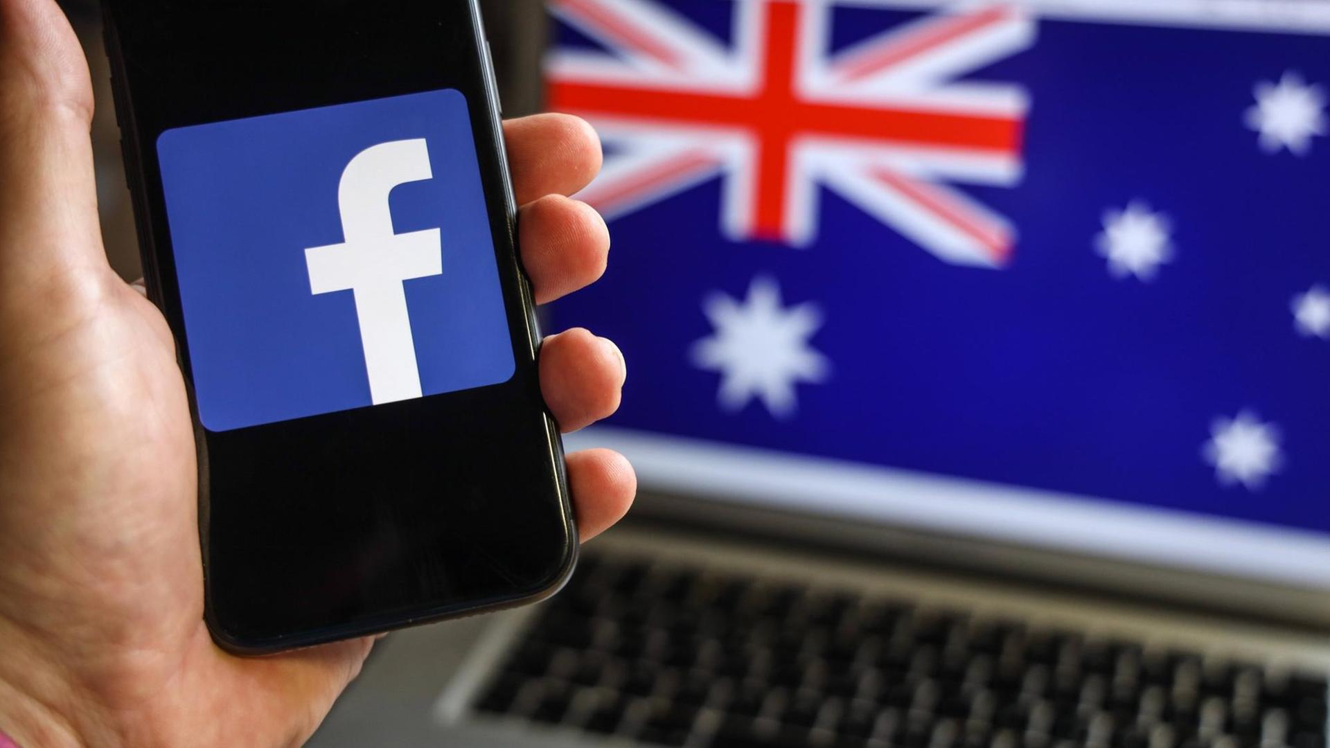 Im Hintergrund ist auf einem Laptop-Bildschirm die australische Flagge zu sehen, im Vordergrund auf einem Smartphone das Logo von Facebook. Im Hintergrund ist auf einem Laptop-Bildschirm die australische Flagge zu sehen, im Vordergrund auf einem Smartphone das Logo von Facebook.