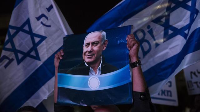 Unterstützer von Israels Ministerpräsident Benjamin Netanjahu halten bei einer Demonstration in Tel Aviv Plakate des Politikers hoch