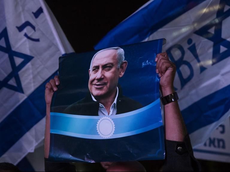 Unterstützer von Israels Ministerpräsident Benjamin Netanjahu halten bei einer Demonstration in Tel Aviv Plakate des Politikers hoch