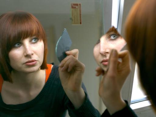 Eine Frau blickt in einen Spiegel.