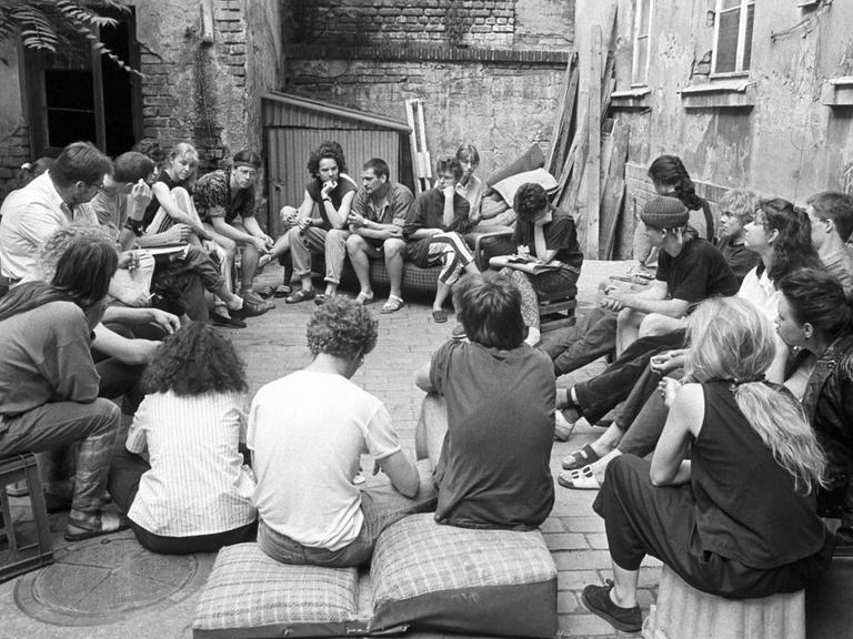 In Leipzig-Connewitz sitzen Jugendliche im Mai 1990 im Hinterhof eines Abrisshauses. Mit der Wende wurde viele leerstehende Häuser von sogeannten Instand-Besetzern bezogen.