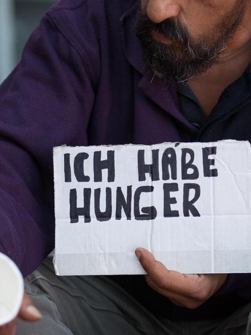 Ein Bettler hält am 14.09.2016 in Münster (Nordrhein-Westfalen) einen Becher und ein Schild mit der Aufchrift "Ich habe Hunger".